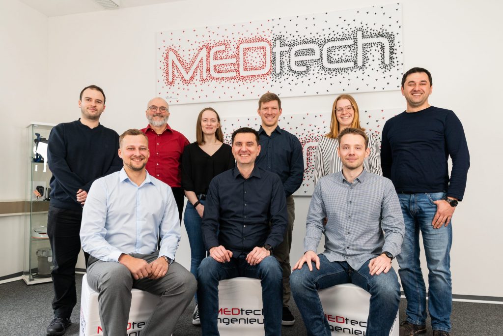 Team von MEDtech Ingenieur vor dem Unternehmensschriftzug